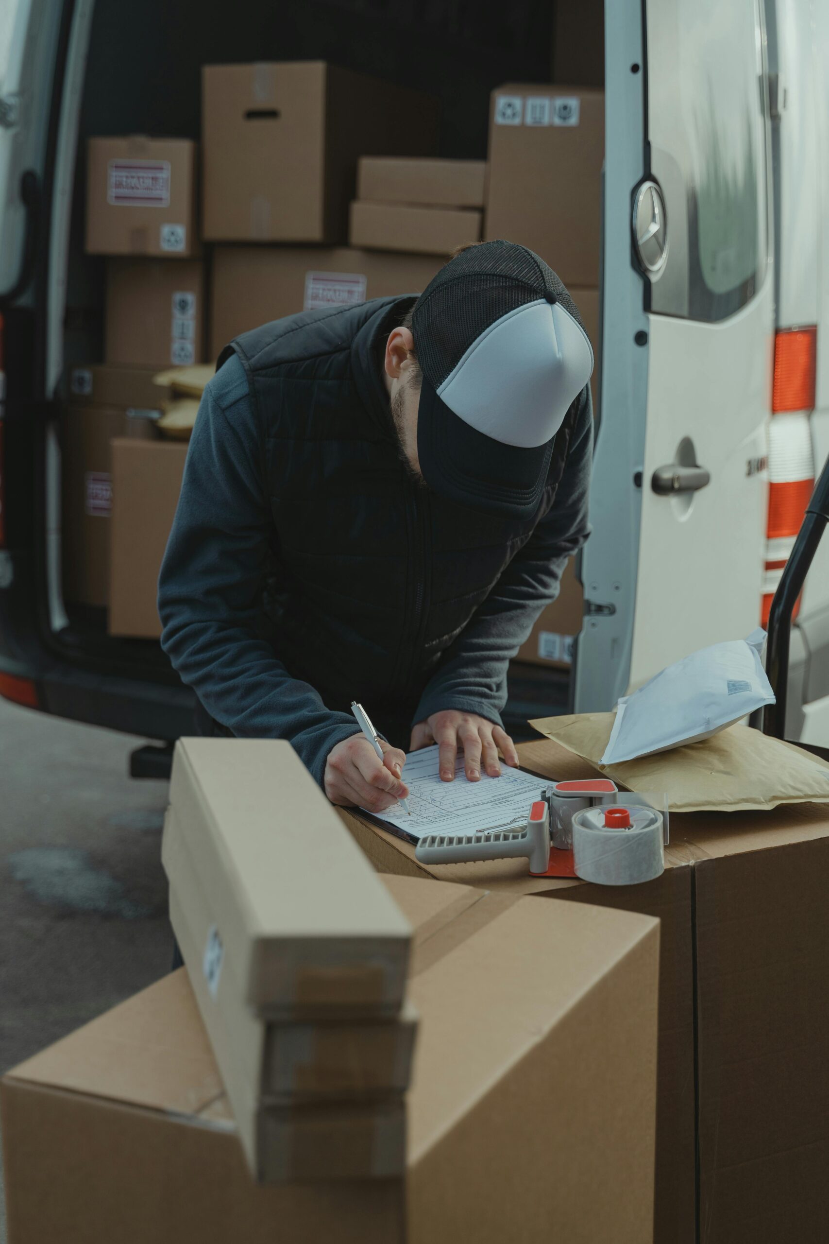 Home Courier organizing packages from a van, preparing for delivery in a logistics setting.